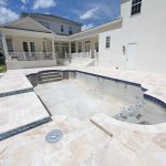 Custom residential pool under construction with spa and travertine deck, showing how long does it take to build a pool in Florida