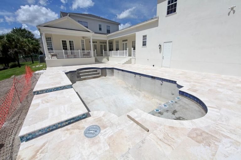 Custom residential pool under construction with spa and travertine deck, showing how long does it take to build a pool in Florida